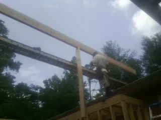 Carpenter setting a ridge beam over a new addition frame — Ice Dam Removal by Roofing Brothers in Nunda