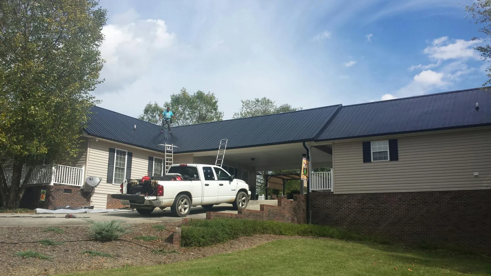 Black metal roof over a home and attached breezeway with ladders set in Nunda