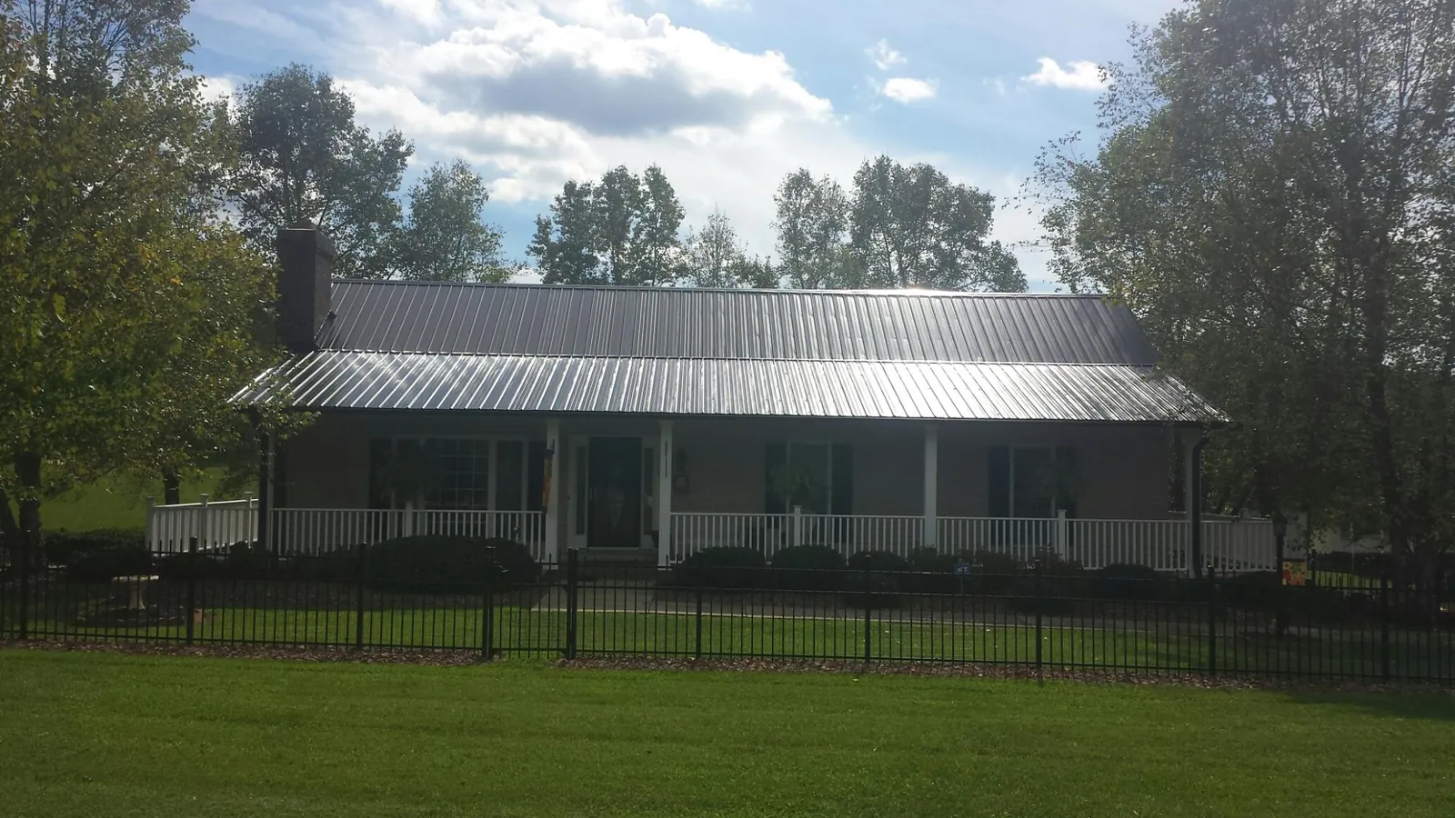 Gray metal roof on a brick ranch with a full width front porch — Gutter Guard Installation work by our crew in Nunda