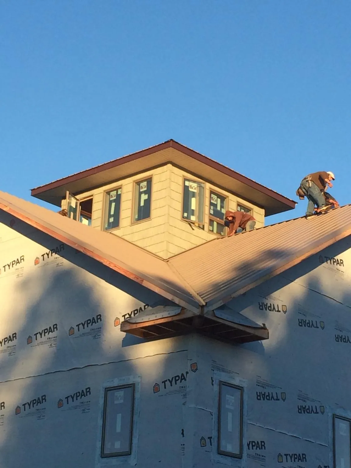Roofers working around a rooftop cupola on a new metal roof at sunset — Roof Waterproofing in Nunda by Roofing Brothers